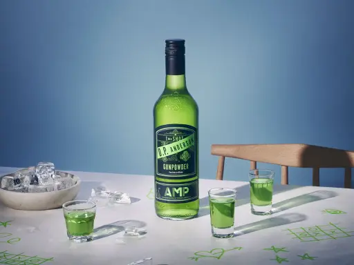 O.P. Anderson Gunpowder i gröna shotglas på ett bord med is och tic-tac-toe-ritningar.