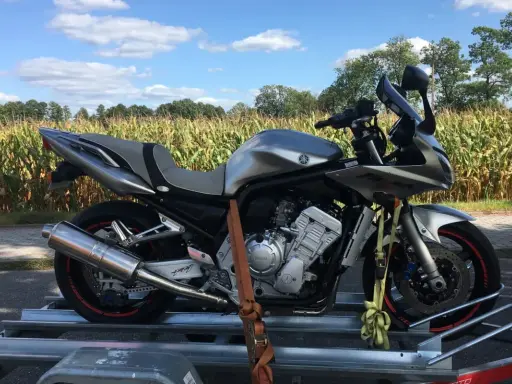 Srebrny motocykl na przyczepce, gotowy do transportu. Może to być związane z akcyzą na motocykle, która wpływa na koszty zakupu.