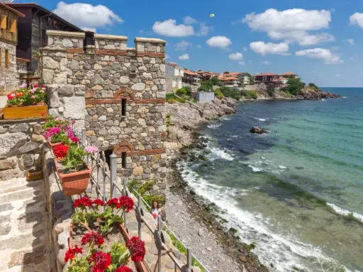 Kamienna twierdza nad morzem, kwitnące pelargonie. Widok na wybrzeże i miasteczko. Czy w Bułgarii jest bezpiecznie? Tak, to urokliwe miejsce.