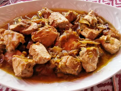 Sabroso bonito en escabeche, trozos de pescado tierno con cebolla en una salsa dorada.