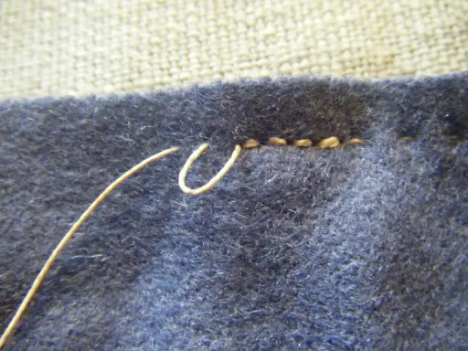 En tråd används för att sy ihop stickat med efterstygn. En del av stygnen syns tydligt.