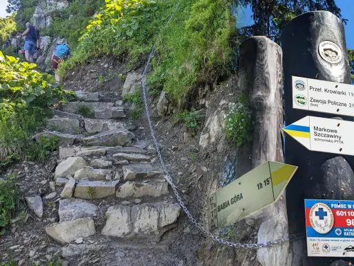 Kamieniste schody i łańcuch na Babiej Górze, szlak Perć Akademików. Znaki kierunkowe wskazują drogę do Markowych Szczawin.