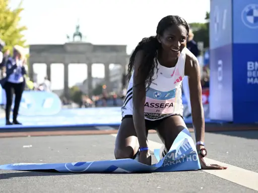 Glückliche Ruth Chepngetich kniet am Ziel des Berlin Marathons, die Ziellinie überquert.