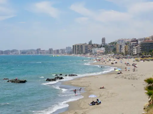 Sonniger Benalmadena Strand mit vielen Menschen, bunten Sonnenschirmen und dem türkisfarbenen Meer.