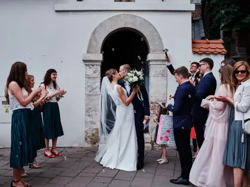 Para młoda całuje się przed kościołem, goście sypią bańki mydlane. To piękny ślub jednostronny, przysięga miłości.