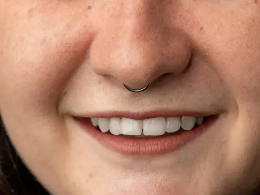Uśmiechnięta twarz z kolczykiem w nosie (septum).