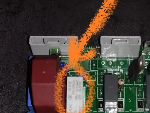 Carte mère de poêle à granulés avec un problème. On voit des connecteurs, des composants électroniques et une trace orange.