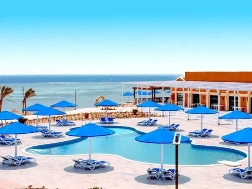 Basen z niebieskimi parasolami i leżakami, widok na morze. Idealne miejsce na wakacje, jak w Pickalbatros Portofino Marsa Alam.