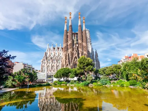 La Sagrada Familia, con le sue torri svettanti e il riflesso sull'acqua, sembra un sogno che attende il suo completamento. Chissà quando finirà la Sagrada Familia.