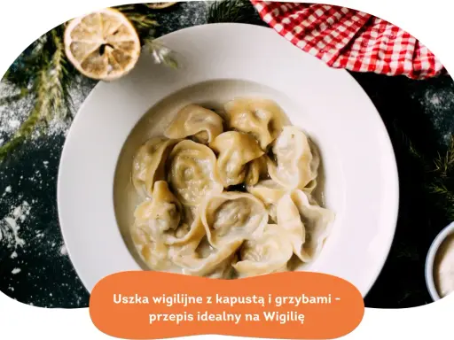 Pyszne uszka z grzybami, idealne na Wigilię, podane w białej misce, ozdobione gałązkami choinki i plasterkiem cytryny.