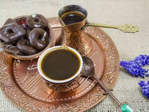 Ein traditionelles Mokkakännchen mit starkem Kaffee, dazu Schokoladenkekse und blaue Blumen. Was ist Mokka? Ein Genuss für die Sinne.