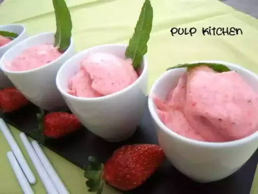 Délicieuse mousse fraise dans des coupelles blanches, garnie de menthe. Fraises fraîches et bâtonnets complètent cette gourmandise.