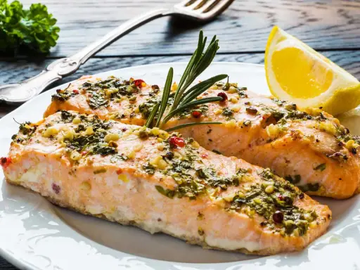 Två saftiga laxfiléer med en härlig pesto-topping, garnerade med rosmarin och en citronklyfta.