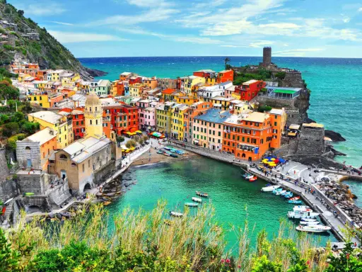 Vernazza, una delle Cinque Terre, con case colorate a picco sul mare turchese e un porticciolo pieno di barche.