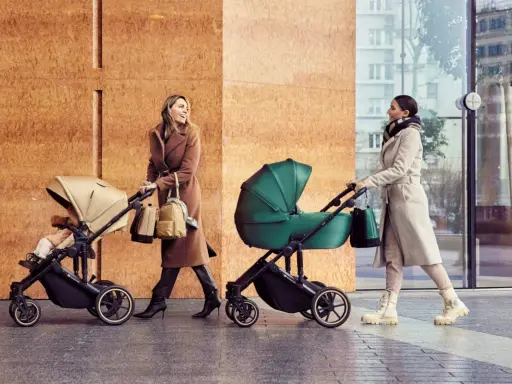 Dwie kobiety spacerują z wózkami Kinderkraft Route. Jedna w beżowym płaszczu, druga w jasnym.