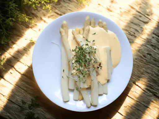 Vitt sparris på en tallrik med en krämig sås och färska örter. Perfekt att koka sparris till en lätt och god måltid.