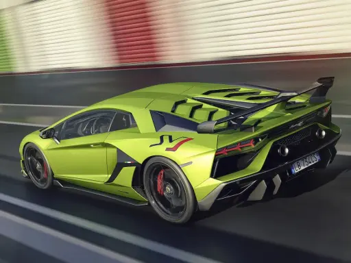 Un espectacular Lamborghini Aventador verde acelera en la pista, con su alerón trasero y detalles aerodinámicos en negro.