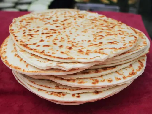Una pila di piadine dorate, appena sfornate, con macchie di cottura che invitano a gustare questo classico della cucina romagnola.