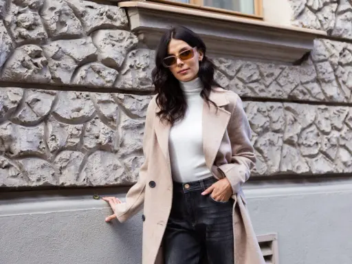 Elegancka kobieta w beżowym płaszczu i ciemnych jeansach. Spódnica jeansowa midi stylizacje na co dzień.