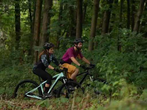 Para jadąca na rowerach górskich (MTB) przez las. Czy to szlak gravelowy czy terenowy?
