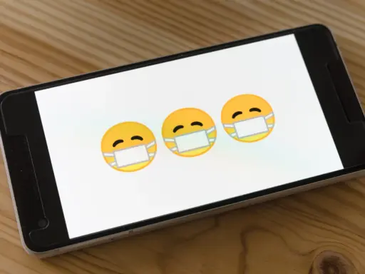 Trzy emoji w maseczkach na ekranie smartfona. Dowiedz się, jak usunąć wirusy z iPhone.