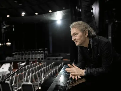 Tomas Ledin lutar sig mot en pianokant i en tom teatersalong, kanske förbereder han sig för Melodifestivalen.