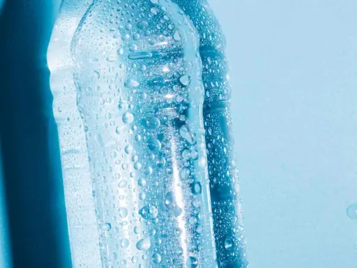 Krople wody na plastikowych butelkach, sugerujące, czy można zamrozić wodę w butelce plastikowej.