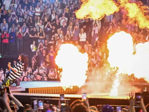 Billie Eilish ger en elektrisk Billie Eilish konsert med flammor som exploderar runt henne. Publiken filmar med sina mobiler.