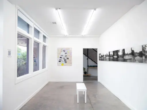 Inside the Atlanta Center for Photography, a white bench sits before a map artwork. Black and white photos line the opposite wall.