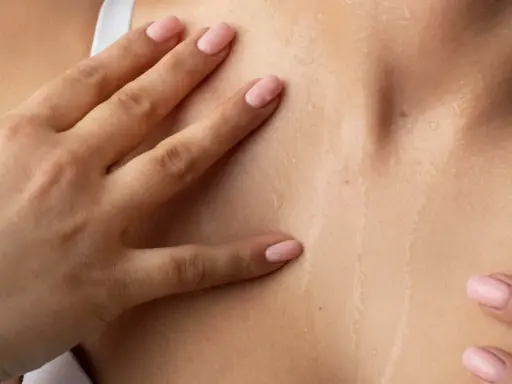 Mani accarezzano la pelle naturale cos'è: idratata e luminosa, con goccioline d'acqua che riflettono la luce.