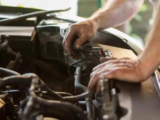 Mecánico revisa el motor de un coche. El sonido de aire al acelerar el coche podría ser un problema.