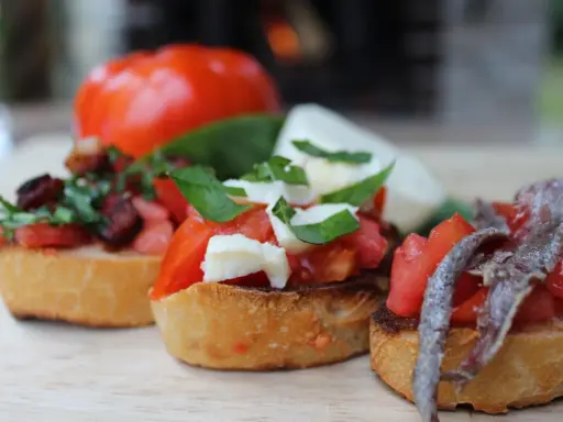 Drei italienische Bruschetta mit Tomaten, Mozzarella und Sardellen auf geröstetem Brot.