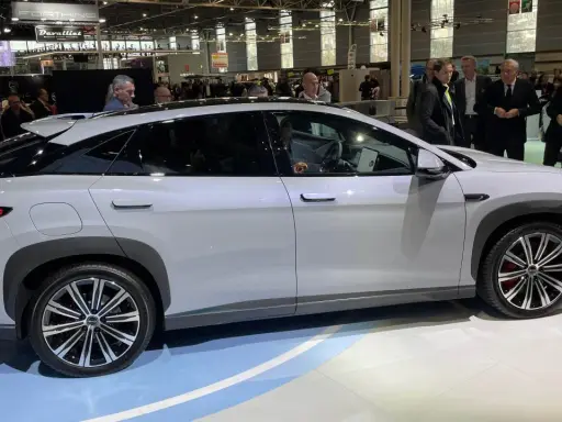 En vit BYD-bil visas på en mässa. Människor tittar på bilen, kanske potentiella byd återförsäljare.