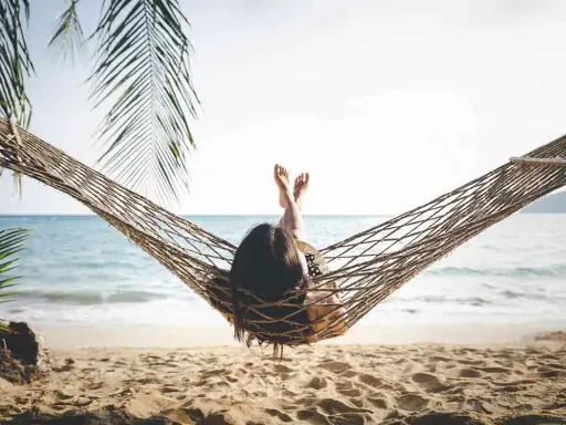 Relaks na plaży w hamaku, idealny opis wakacji po angielsku. Słońce, morze i palmy tworzą rajski widok.