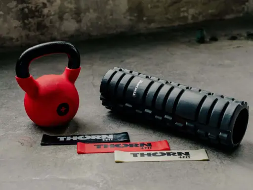 Czerwony kettlebell, wałek do masażu i taśmy oporowe. Idealny zestaw, by zacząć treningi z kettlebell.