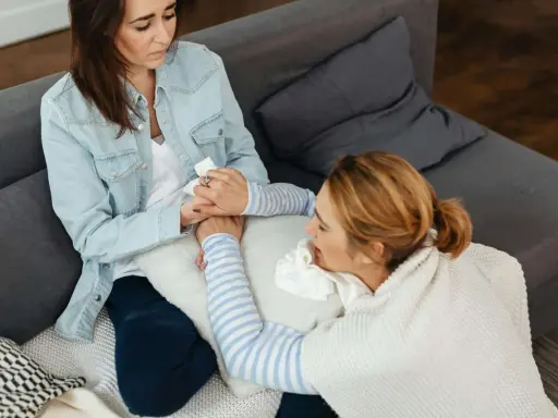 Dos mujeres sentadas en un sofá, una consolando a la otra. La codependencia es una enfermedad que puede afectar a cualquiera.