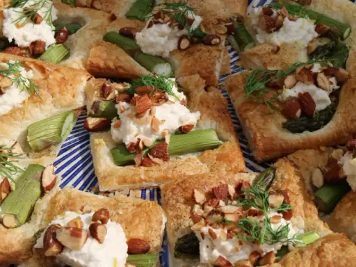 Veganska snittar med sparris, krämig topping och hackade nötter på en blåvitrandig tallrik. En festlig och god förrätt.
