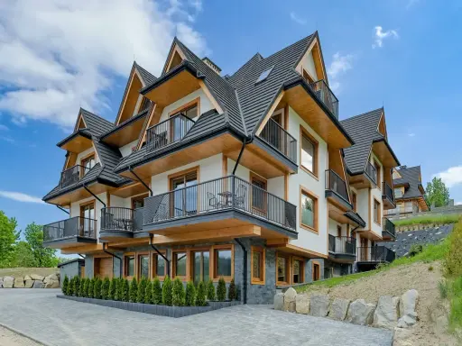 Nowoczesne apartamenty Bachledzki Wierch z drewnianymi elementami i balkonami, otoczone zielenią.