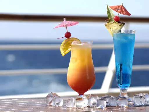 Due cocktail colorati, un tramonto e un blu intenso, decorati con ombrellini e frutta, perfetti per godersi i pacchetti bevande MSC in crociera.