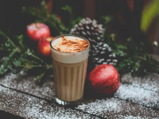 En krämig kaffedrink med kanel, omgiven av juliga äpplen och granris. Perfekt för mysiga stunder och inspirerar till egna kaffedrinkar recept.