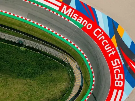 Vista aerea del circuito di Misano, con la scritta "Misano Circuit Sic58" in rosso e un disegno colorato.