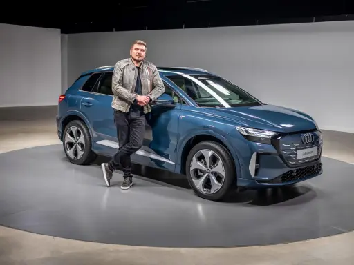 Ein Mann lehnt lässig an einem blauen Audi Q4 e-tron 2026.