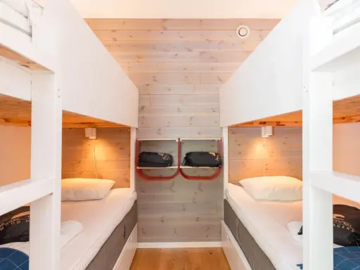 Två våningssängar i en mysig stuga, perfekt för camping i Åre. Sängkläder och sovsäckar redo för äventyr.