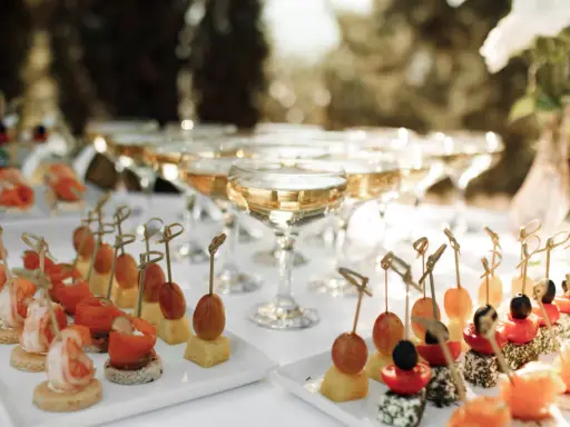 Elegantes aperitivos para bodas: camarones, salmón, queso y frutas en brochetas, junto a copas de champán.