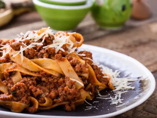 Pappardelle z bogatym sosem bolognese, idealne pytanie: jakie mięso do spaghetti? Posypane parmezanem.