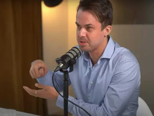 Michael van de Poppe w niebieskiej koszuli mówi do mikrofonu, gestykulując.