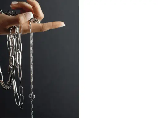 Mano con anelli che mostra diverse collane Pesavento, con maglie lucide e un design moderno. Scopri i prezzi.