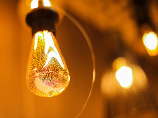 Une ampoule décorative aux filaments lumineux, projetant une lumière chaude et dorée. L'étiquette ampoule est subtilement intégrée dans le design.