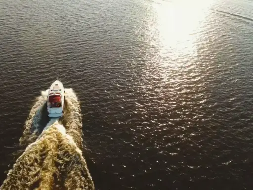 Bateau blanc naviguant sur l'eau sombre, laissant une traînée écumeuse. Le soleil brille, rappelant le temps de séchage Sikaflex.