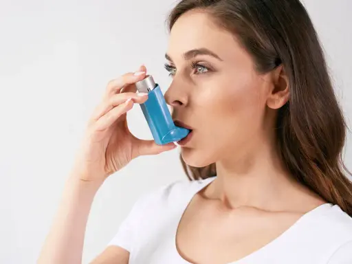 Frau mit Inhalator, der bei Asthma hilft. Hohe Luftfeuchtigkeit kann Symptome verschlimmern.